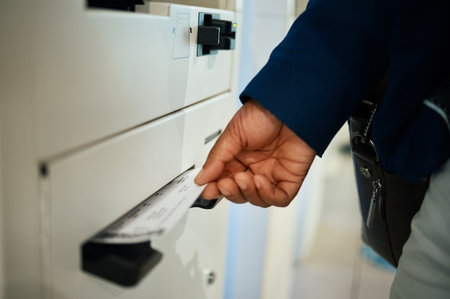 Hands, ticket and airport at self service machine for check in, flight or boarding pass to travel. Hand of traveler taking plane tickets for traveling, trip or journey at airline auto terminalの写真素材