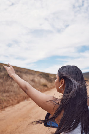 Travel, road trip and woman with hand out car, having fun and enjoying time outdoors. Adventure, freedom and girl or female on a drive in nature, desert or safari on holiday, vacation or journey.の写真素材