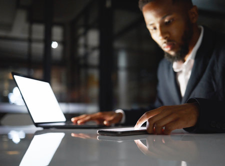 Laptop screen, phone and black man at night for fintech management, trading and stock market data analysis. Finance, accounting and business person with omnichannel for global investment and mockupの写真素材