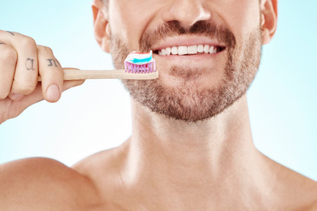 Smile, mouth or happy man brushing teeth with dental toothpaste for healthy oral hygiene grooming in studio. Eco friendly, zoom or male model cleaning with a smile or natural bamboo wood toothbrushの写真素材