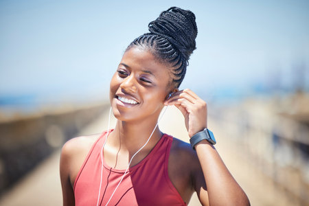 Fitness, black woman and happy runner with earphones for training exercise outdoor. Face, smile and female athlete listening to music for sports motivation, healthy goals and audio of running workoutの写真素材