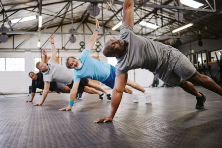 People, fitness and side plank in class with personal trainer for workout, stretching exercise or...