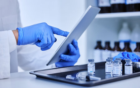 Logging every dose. an unrecognizable scientist working on a tablet in the lab.の写真素材