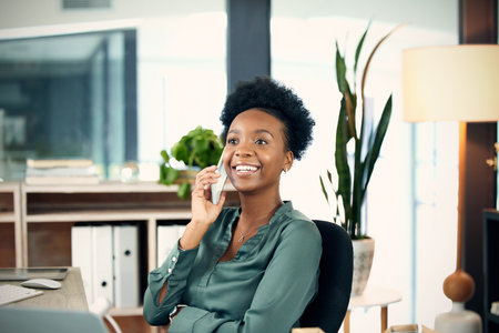 Calling up a client with some updates. a young businesswoman talking on a cellphone in an office.の写真素材