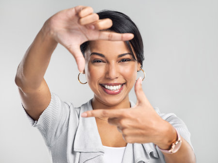 Dream bigger, do better. Studio shot of a confident young businesswoman making a frame with her fingers against a grey background.の写真素材