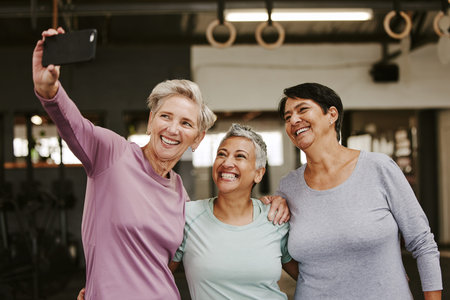Selfie, friends and senior women in gym taking pictures for happy memory together. Sports, laughing and group of retired females taking photo for social media post after workout, training or exerciseの写真素材