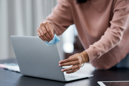 You cant be too careful when it comes to hygiene. an unrecognisable woman disinfecting her laptop...