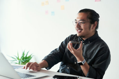 Im looking at the proposal right now. a handsome young businessman making a phone call while working in his office.の写真素材