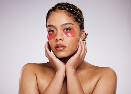 Black woman, eye mask and beauty portrait with skin care, cosmetics and dermatology in studio. Face of aesthetic model person on a grey background with facial collagen gel patch for wellness glowの写真素材
