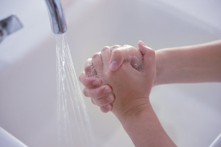Hygiene, above and person washing hands with water for health, disinfection and virus protection. Soap, healthy and liquid from a basin to wash, clean and prevent disease on fingers of a humanの写真素材