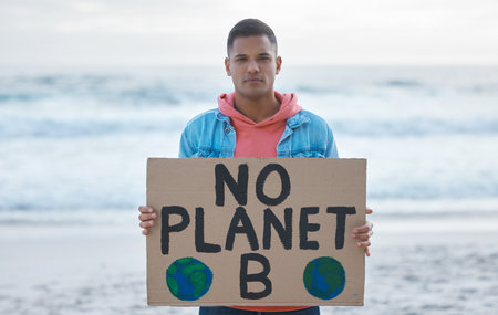 Save earth, sign and man protest at beach pollution, environment and green, eco planet. Ocean, sea and portrait of person with nature globe poster for awareness, global warming and climate changeの写真素材