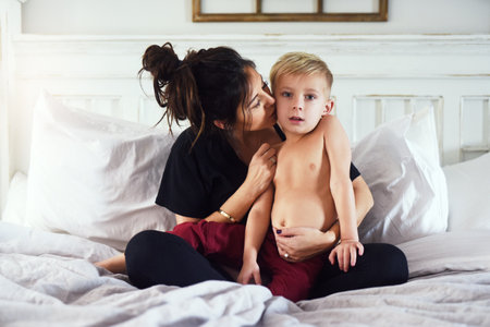 Never grow up my dear. a cheerful little boy and his mother hanging out on the bed at home while relaxing during the day.の写真素材
