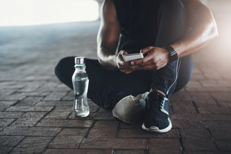 Resting up between sets. an unrecognizable young man sending a text while exercising outside.