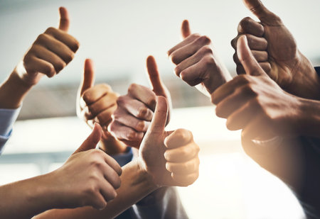 Do us proud. Closeup shot of a group of businesspeople showing thumbs up in an office.の写真素材