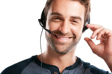 How may I be of service. Studio portrait of a handsome young man using a headset against a white background.の写真素材