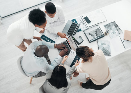 Business people, laptop and meeting in web design above for planning, strategy or brainstorming at the office. Top view of group designers working on computer for team project plan or idea on tableの写真素材