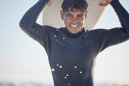 Portrait, vacation and man holding surfboard at the beach, sea or ocean with a smile and is happy on a summer day. Man, surfing and male surfer with swimsuit in Australia with freedom on the wavesの写真素材