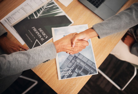 Top view, handshake or teamwork collaboration in meeting designer company, global marketing or advertising office. Manager, ceo or leadership shaking hands with worker, employee or partnership womanの写真素材