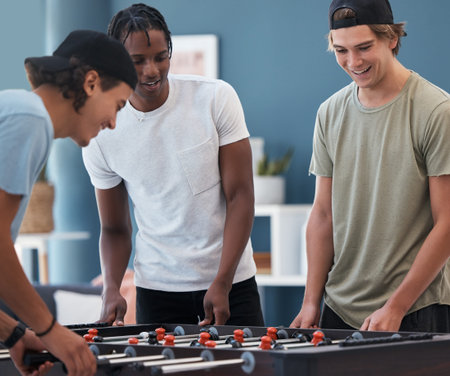 Student foosball, friends and men playing a game at students accommodation at university. Board,...