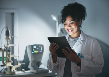 Tablet, medical doctor and black woman in hospital for online consultation, research or telehealth at night. Healthcare clinic, technology and happy female physician with touchscreen for wellness appの写真素材