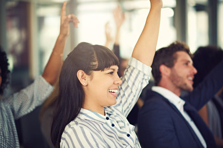 Learning new business techniques at the seminar. a beautiful young businesswoman asking a question during a seminar.の写真素材