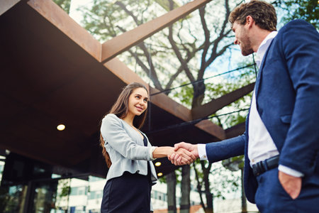 Meeting businesspeople from all over. a businesswoman and businessman shaking hands outside.