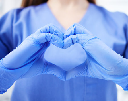 Woman, doctor and hands in heart emoji for healthcare, life insurance or sign on mockup at hospital. Hand of medical female expert GP showing love, hearty symbol or gesture for medicare assuranceの写真素材