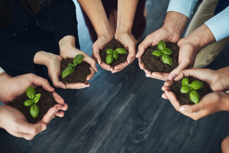 Grow your business from the ground up. a group of businesspeople holding plants growing out of soil.の写真素材