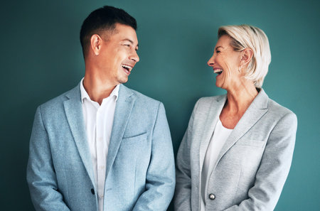 Mockup, business people and laughing team in studio for fun and happy conversation or comedy on green background.Partnership and man with senior woman with humor, joke or discussion while isolatedの写真素材