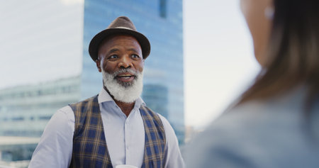 City, black man and woman on rooftop networking, talking or speaking of goals, project development or vision. Team building, relaxing or senior businessman in conversation, communication or chattingの写真素材