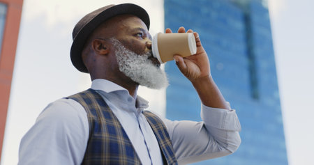 Black senior businessman, coffee and standing city for morning routine, positive mindset vision and remote travel for work. African man, drinking tea and thinking outdoor in New York for travelingの写真素材