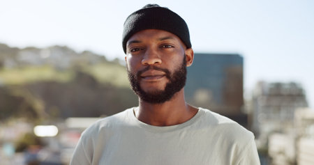 Face, confident and city with an edgy black man outdoor in an urban town for fashion or street style. Portrait, cityscape and lifestyle with a young African American male outside on a summer dayの写真素材