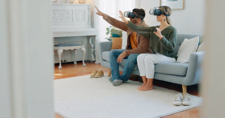 VR gamer couple, metaverse or futuristic tech on sofa in living room for cyber game, 3D gaming or future ai media. Virtual reality, video game or esports for technology, digital fun or online fantasyの写真素材