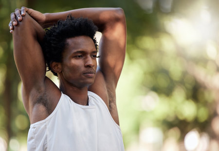 Exercise, fitness and black man stretching arms in nature to start training workout outdoors. Sports, thinking and male athlete stretch, warm up or getting ready for running, exercising or jogging.の写真素材