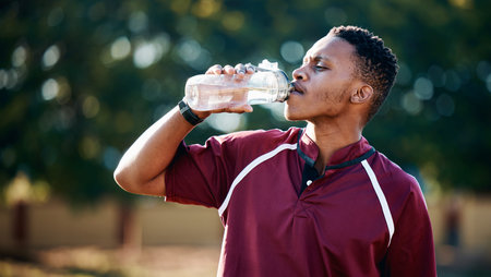 Rugby, sports or black man drinking water in training, exercise or workout match on a field....