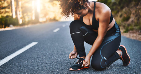 Another day, another goal. a sporty young woman tying her shoelaces before her run.