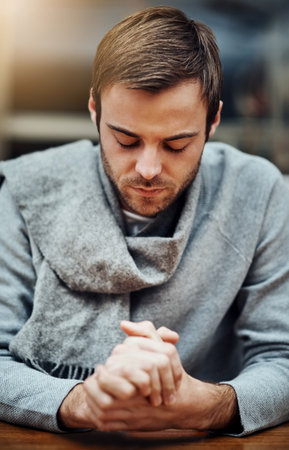 Strength from above. a handsome young man praying for help with his upcoming university exams.の写真素材