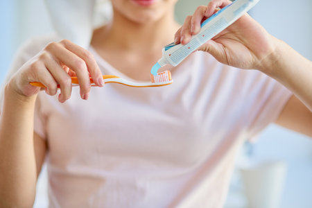 Dont be shy with the toothpaste. an unrecognizable young woman brushing her teeth in the bathroom at home.の写真素材