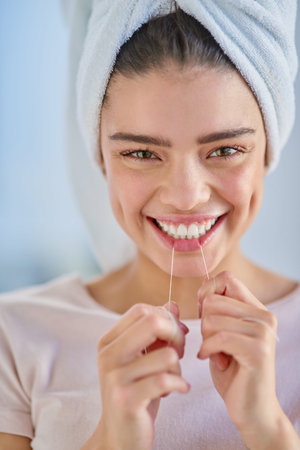 I value my smile. Cropped portrait of a beautiful young woman flossing her teeth in the bathroom at...