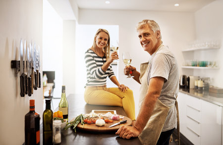 We like to switch things up in the kitchen. a happy mature couple keeping each other company in the kitchen.の写真素材