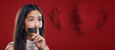 Woman silence, face tape and victim of domestic violence, sexual assault trauma or abuse crime from human trafficking. Red secret mockup, censored speech and young girl scared, fear or quiet gestureの写真素材