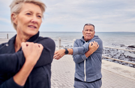 Stretching, fitness and senior couple by ocean for exercise, healthy body and wellness in retirement. Sports, nature and elderly man and woman ready for warm up, cardio workout and training outdoorsの写真素材