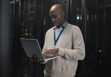 Server room, laptop and black man technician with data center management, system and cybersecurity....