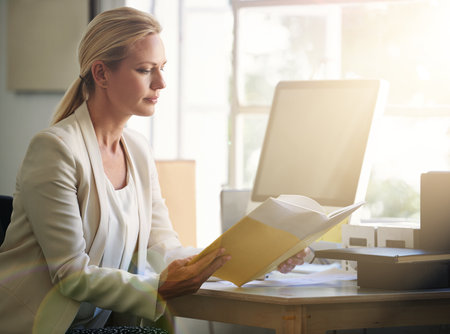 Success isnt given, its earned. a businesswoman reading a book in her office.の写真素材