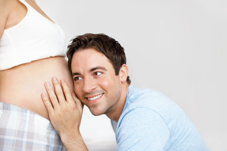 Getting close to his baby - Copyspace. Happy father with his ear next to his wifes pregnant belly.