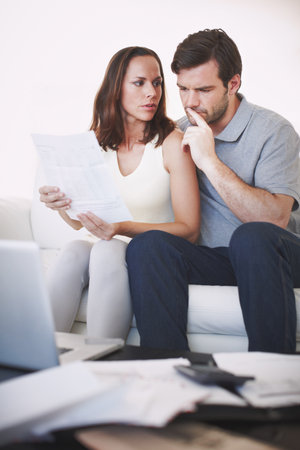 Thinking of some personal finance solutions. A married couple having a serious discussion about their home finances while inspecting a bill.の写真素材