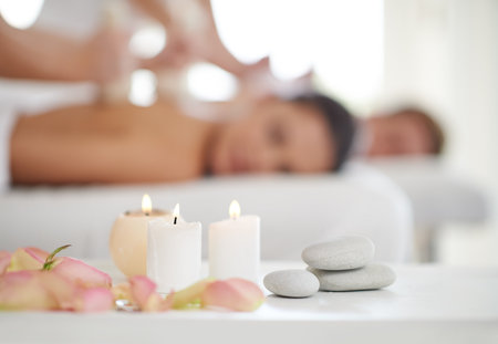 Blissful relaxation. A married couple receiving massages at a spa with candles in the foreground.の写真素材