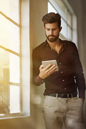 Instant access to the companys online database. a businessman using a digital tablet in his office.の写真素材