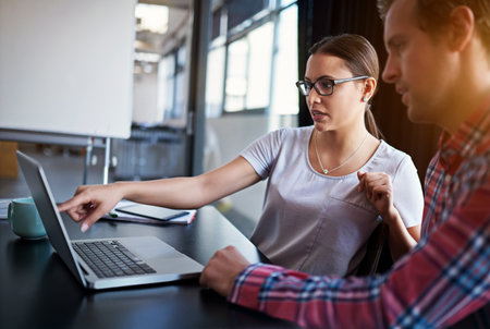 Building their business online platform. Shot of two coworkers having a discussion over a laptop.の写真素材