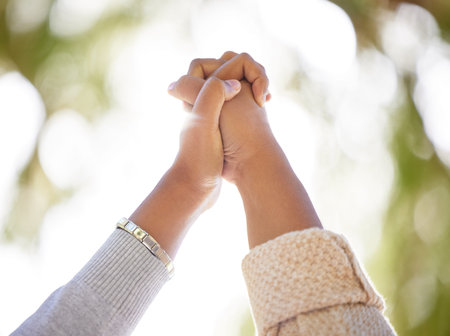 Hand, support or trust with people outdoor together on a nature green background with lens flare in...